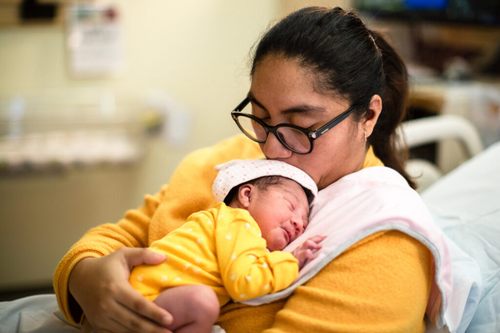 Portraits of a day old Hispanic/Caucasian mixed race baby girl. Shot from over the shoulder of the mother to give focus and perspective to the babies beautiful face.